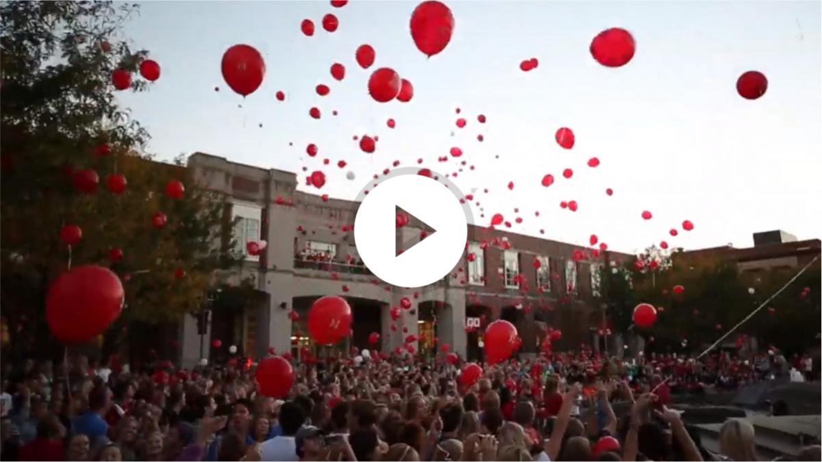 A large crowd assembled in front of the north side of
					 the University of Nebraska-Lincoln's city campus union.
					 Floating up and away from them is a large number of red
					 baloons.