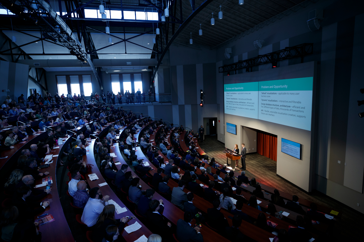 A large auditorium full of people watching a presentation.