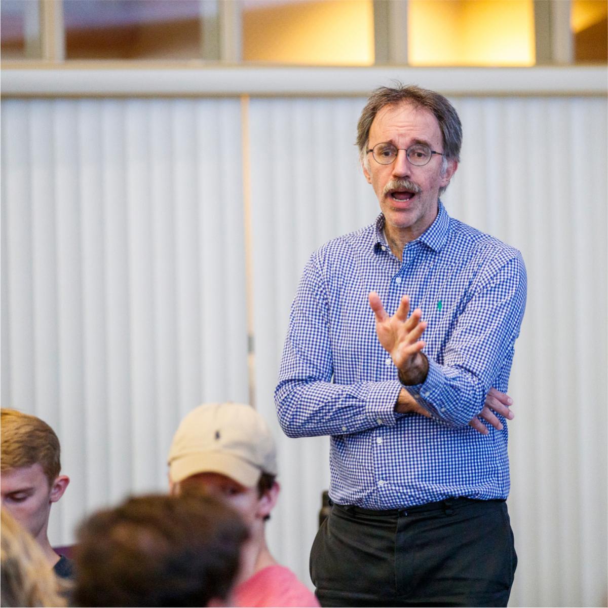 A person standing and speaking in a classroom.