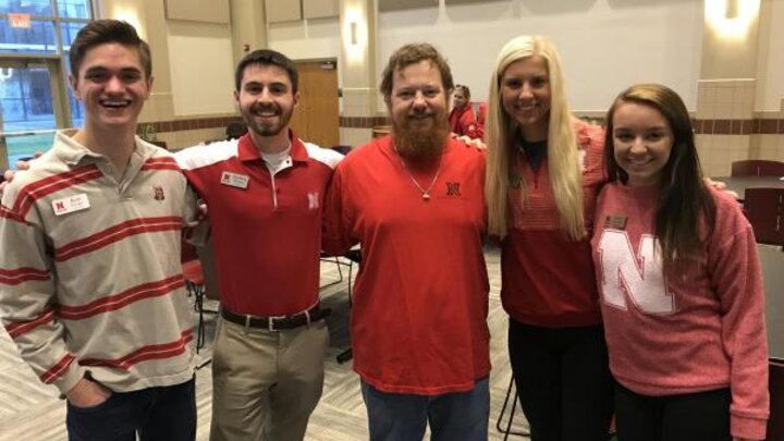 A group of people wearing red and white t-shirts standing in a large room taking a group photograph.