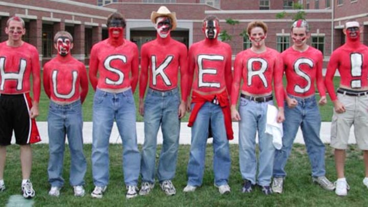 A group of people standing in a line for a photograph with painted chests.