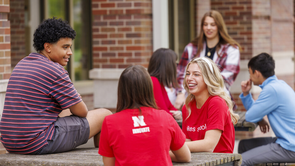 A group of students sitting outside at picnic tables