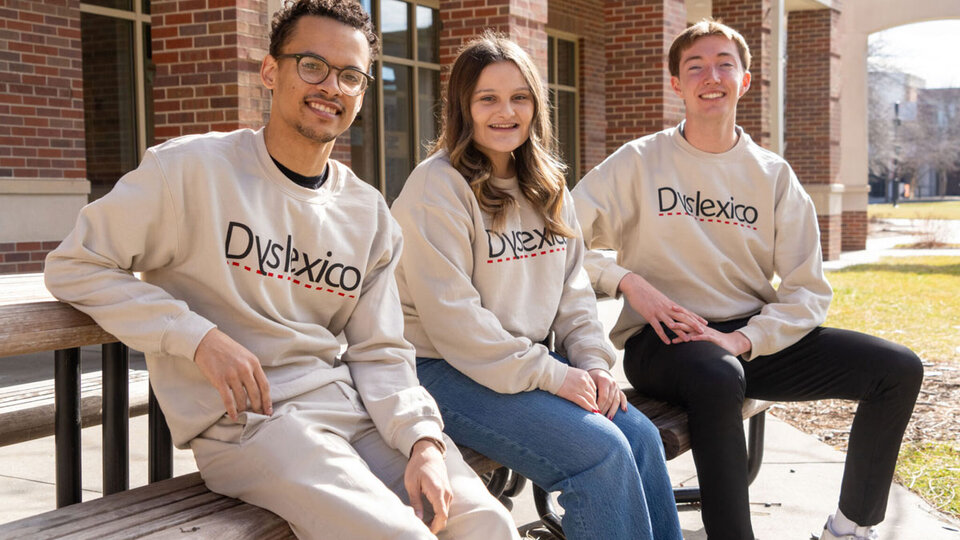 Three students from the Dyslexico team posing on picnic benches outside