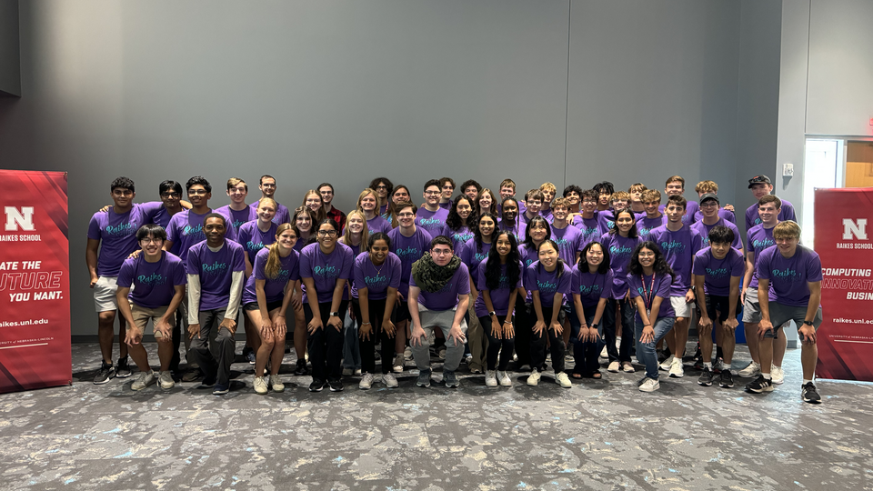 students in a group smiling wearing purple shirts