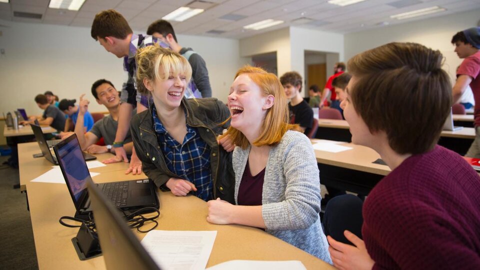 A group of students laughing in a classroom.