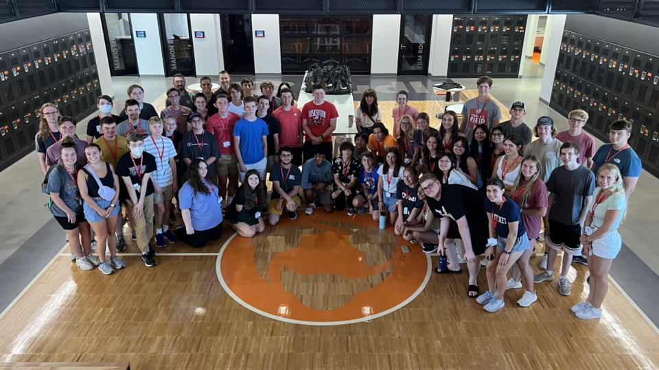 A large group of people assembled on a mock basketball court for a group portrait.