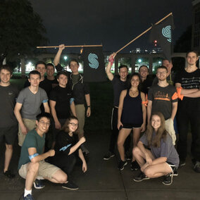 A group of people stood outdoors at night taking a group portrait.