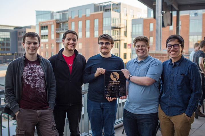 A group of people standing on a balcony with a building in the background taking a group photograph.