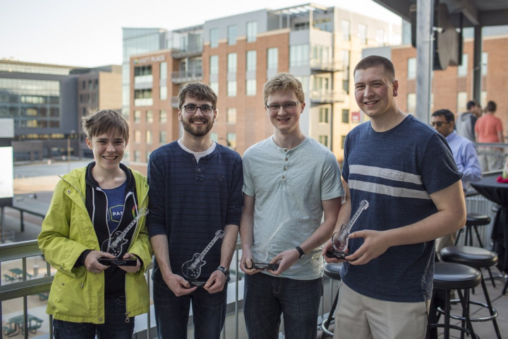 A group of people standing on a balcony with a building in the background taking a group photograph.