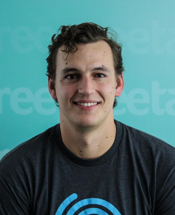 A headshot of a man wearing a black t-shirt against a cyan background.