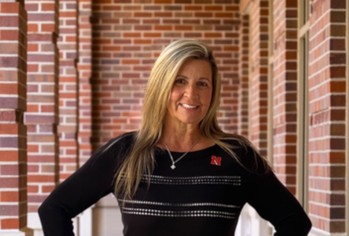 A woman wearing a black sweater standing in front of a brick wall.