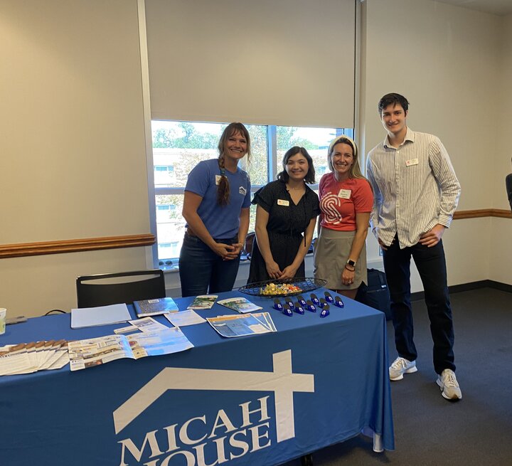 A group of people stood together for a group portrait behind a table covered with leaflets and merchandise.