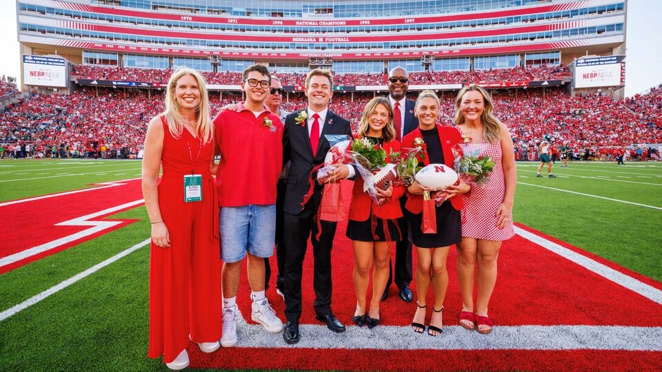 Several individuals stand together for a photo on a football field.
