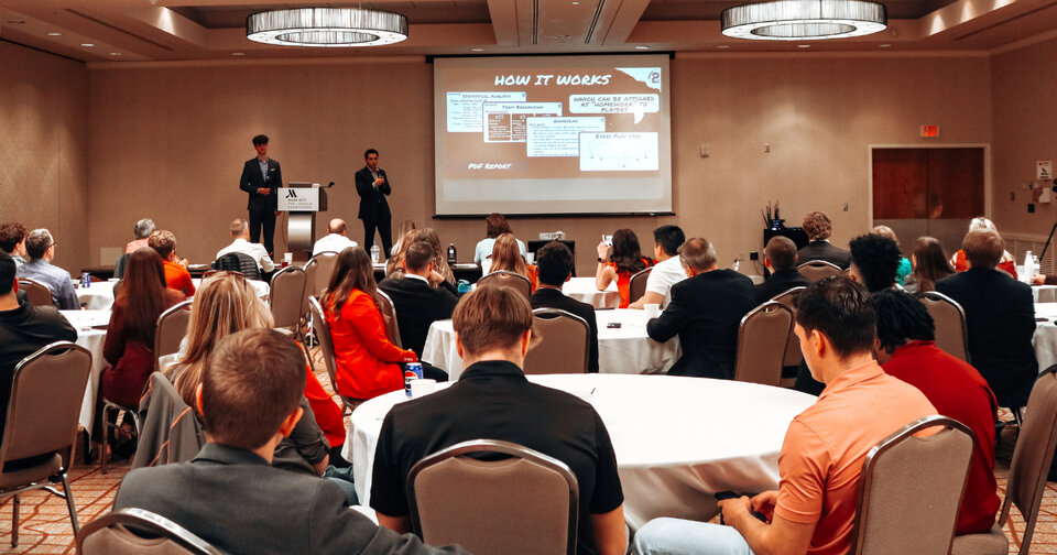 A banquet hall of people watching a presentation.