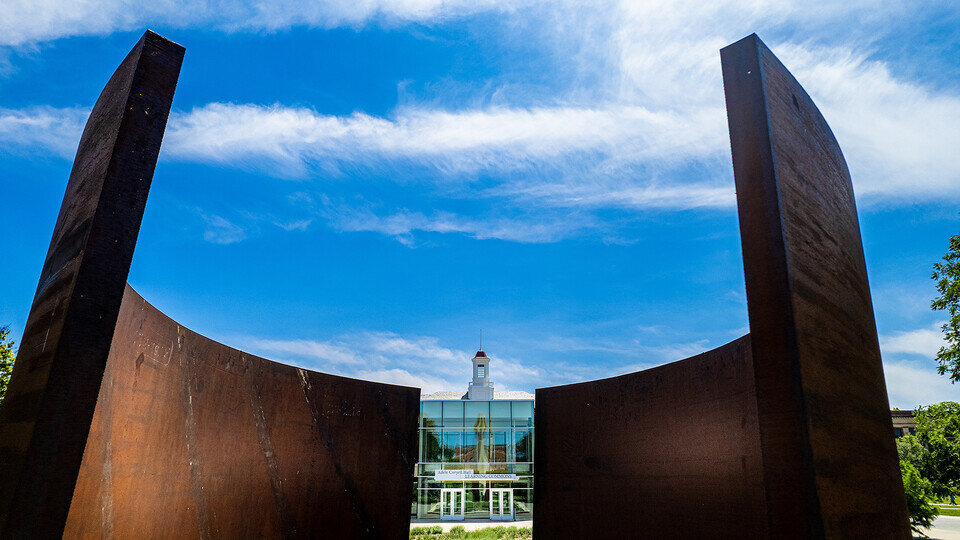 A large metal art installation with a white building visible in the background.