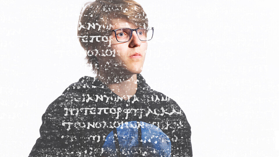 A picture of a man wearing a black and blue sweatshirt, looking at a variety of letters floating in front of him.